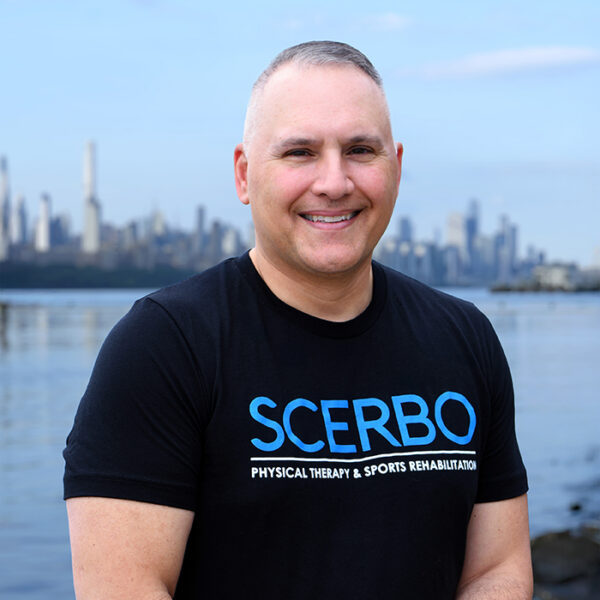 Dr. Frank Scerbo, physical therapist at Scerbo Physical Therapy, standing along the Hudson River Waterfront Walkway with the New York City skyline visible in the background.