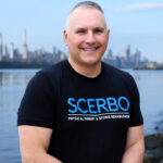 Dr. Frank Scerbo, founder and physical therapist at Scerbo Physical Therapy, standing on the Hudson River Waterfront Walkway with the New York City skyline in the background.