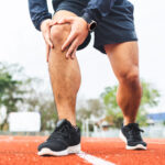 man runner holds knee in pain