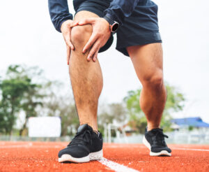 man runner holds knee in pain