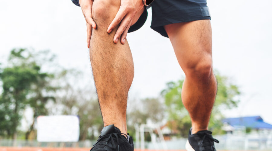 man runner holds knee in pain