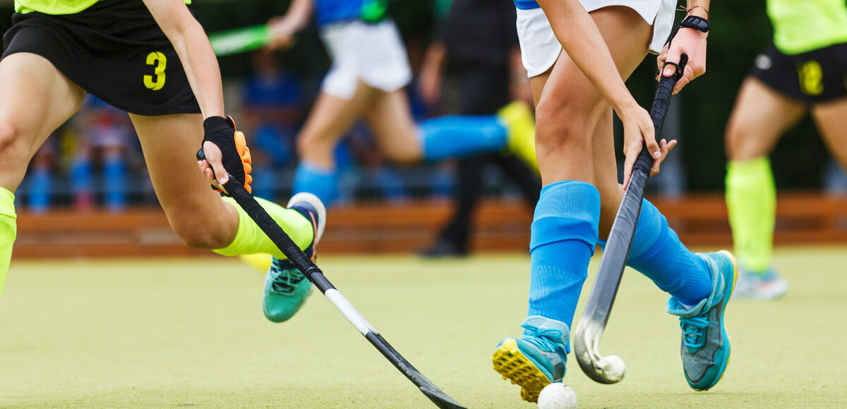 Women's field hockey players in action running after the ball