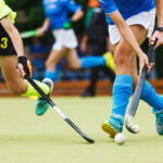 Women's field hockey players in action running after the ball