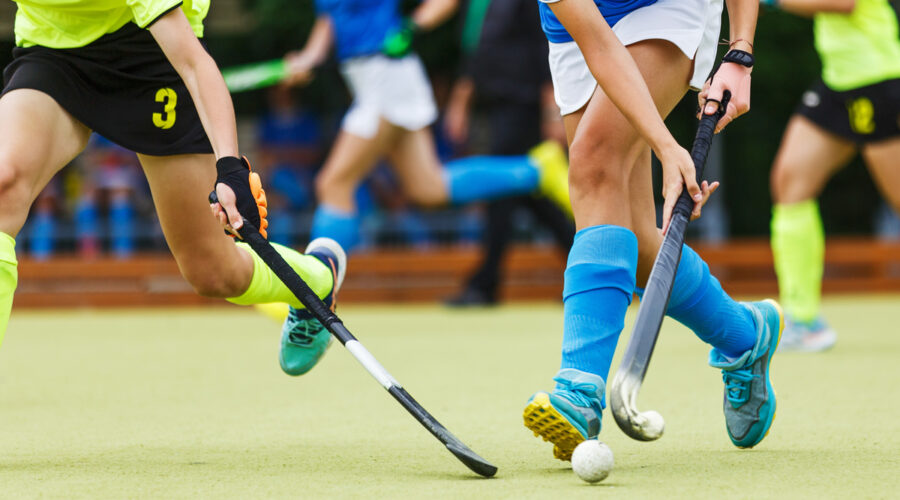 Women's field hockey players in action running after the ball