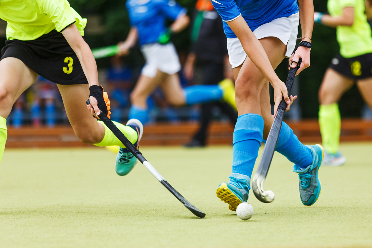 Women's field hockey players in action running after the ball