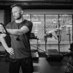 Man doing cable machine lateral raises extension exercises at a gym.