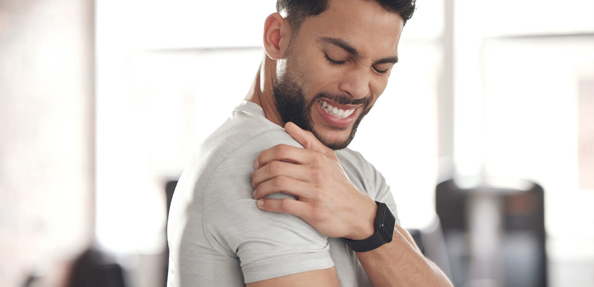 Young athletic man holds his shoulder in pain