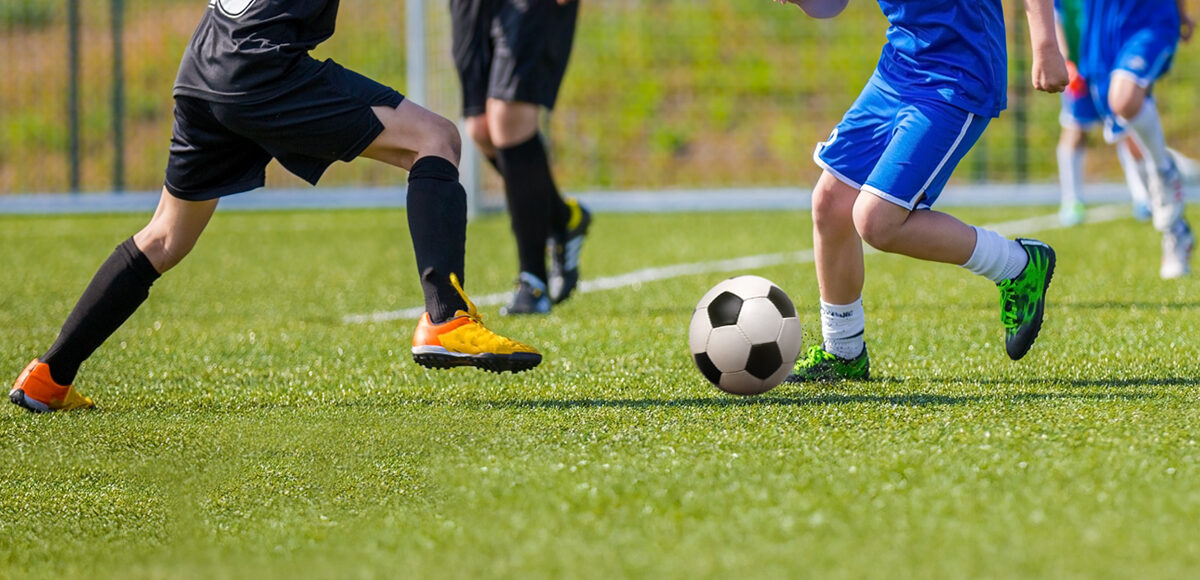 Young teens playing soccer game.