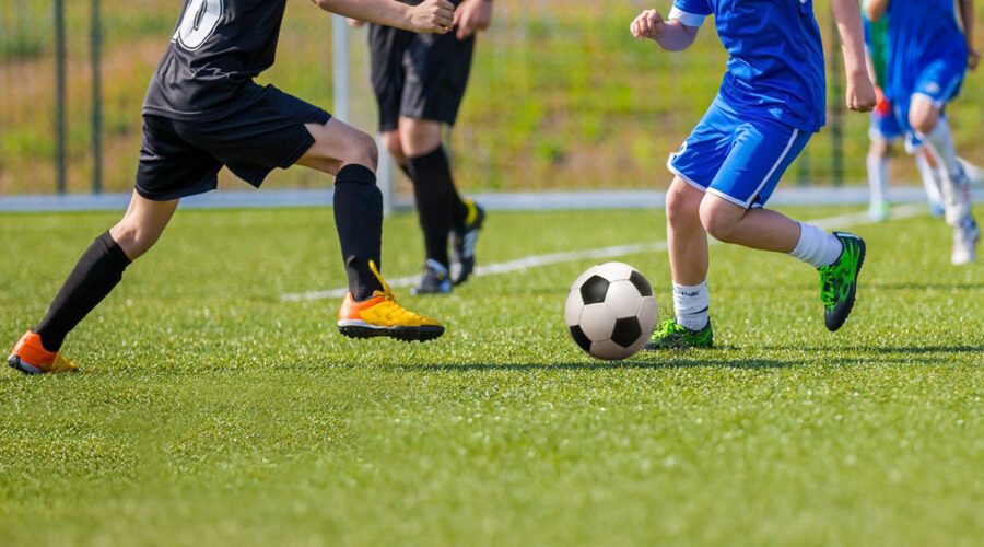 Young teens playing soccer game.