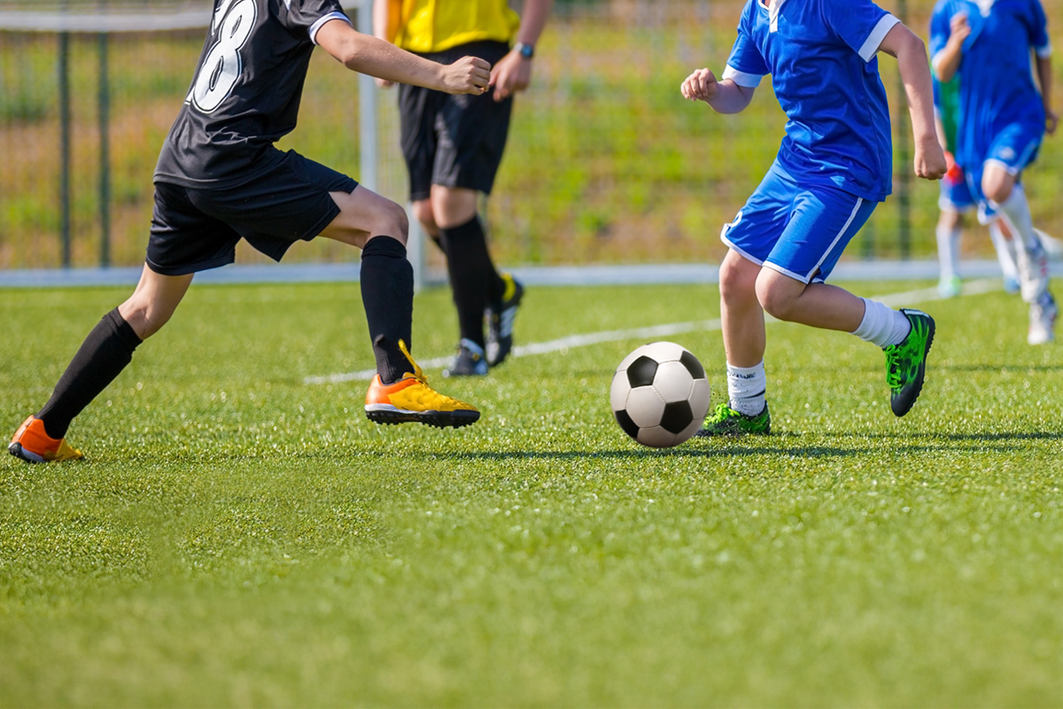 Young teens playing soccer game.