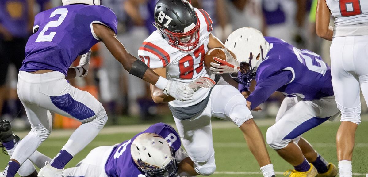 A group of high school football players making an intersection play during a football game
