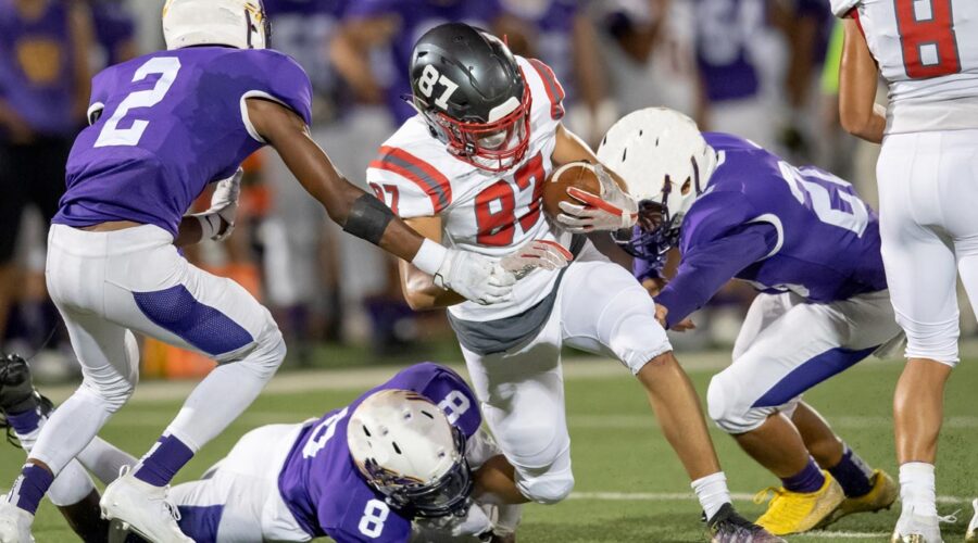 A group of high school football players making an intersection play during a football game