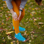 Closeup on woman in fitness clothes in the park having knee joint pain while running in the Park.