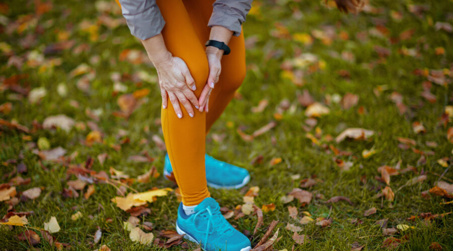 Closeup on woman in fitness clothes in the park having knee joint pain while running in the Park.