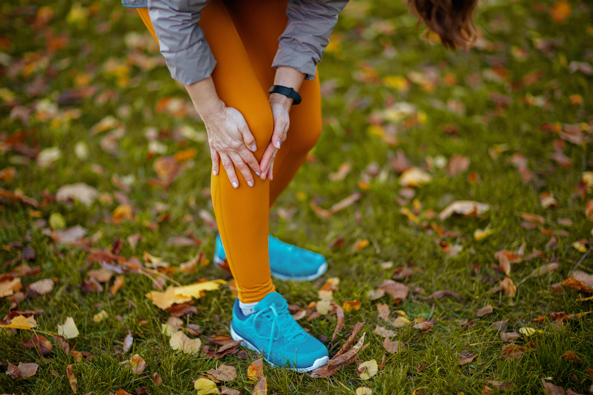 Closeup on woman in fitness clothes in the park having knee joint pain while running in the Park.