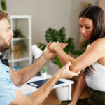 Male physical therapist asses elbow of female patient during a physical evaluation