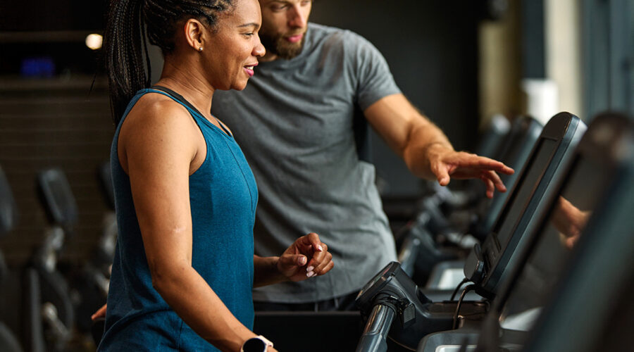 Male physical therapist showing female patient how to setup a treadmill level.