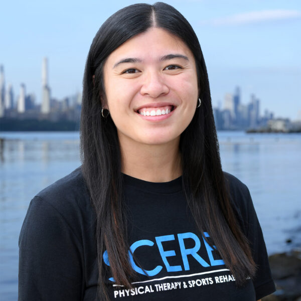 Physical therapist Madelina Bucci standing along the Hudson River Waterfront Walkway with the New York City skyline visible in the background.