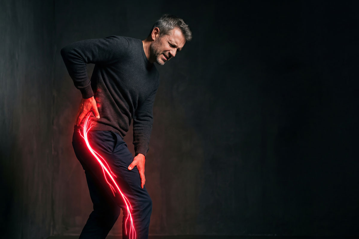 Middle-aged man holding his lower back and hip in pain, with a red and yellow electric spark extending from his hip down his leg to represent nerve pain.